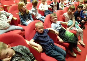 Dzieci siedzą na widowni czekając na rozpoczęcie przedstawienia